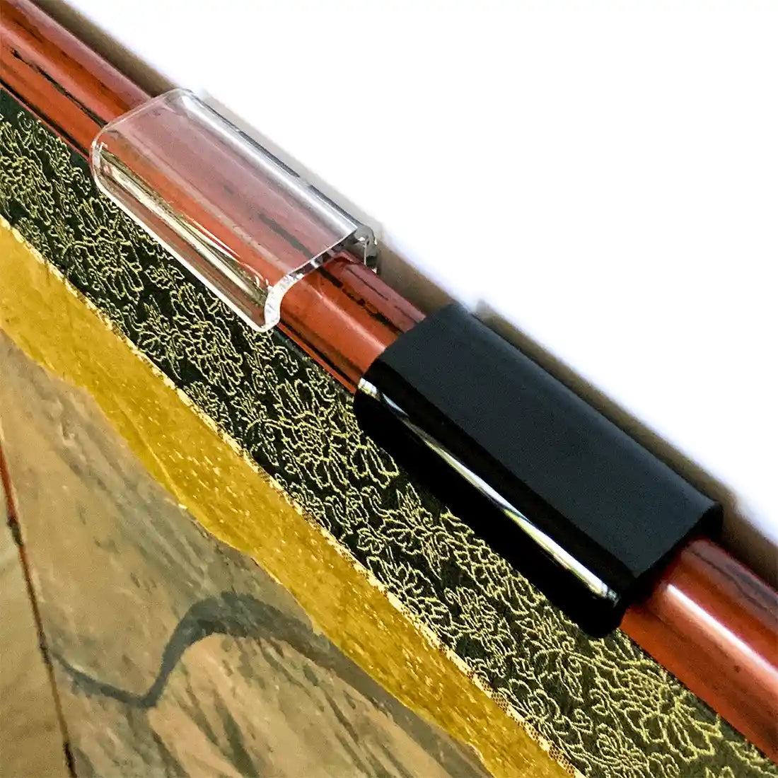 Close-up of clear and black lucite brackets on top edge of a Japanese folding screen.