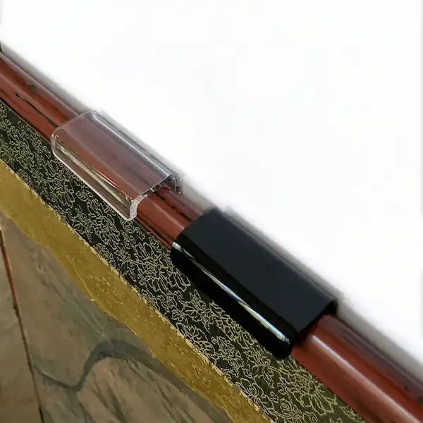 Top view of clear and black lucite brackets  on top edge of a Japanese folding screen.