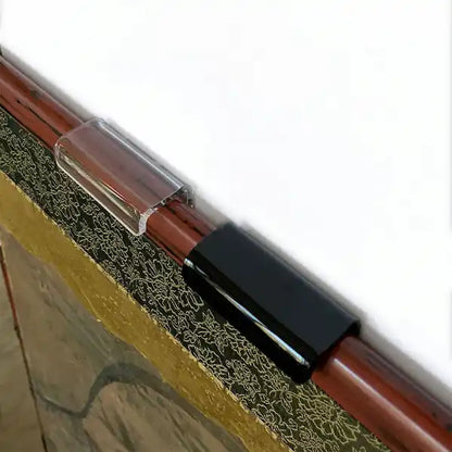 Top view of clear and black lucite brackets  on top edge of a Japanese folding screen.